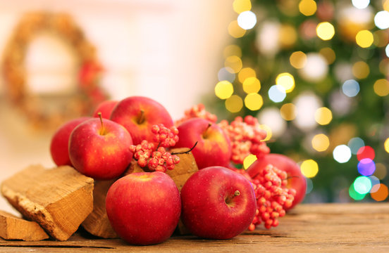 Christmas apples on wooden table on fireplace background