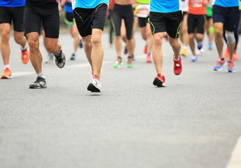 Fototapeta premium Unidentified marathon athletes legs running on city road 