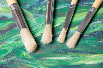 Fototapeta premium close up of paint brushes on green canvas background