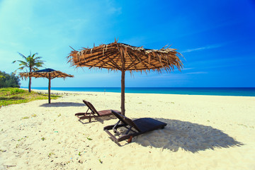 Sun umbrella and sunbed with tourist on the white beach in blue