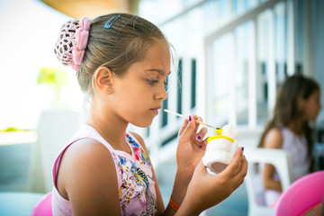 Girl sculpts clay figurines and paints the colors at the table