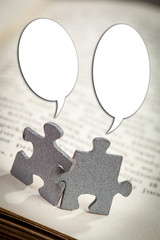 Closeup of Two Jigsaw Puzzle Pieces with Talking Bubbles on Page