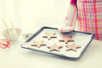 close up of woman with cookies on oven tray