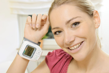 Frau mit Blutdruck-Messgerät an Handgelenk
