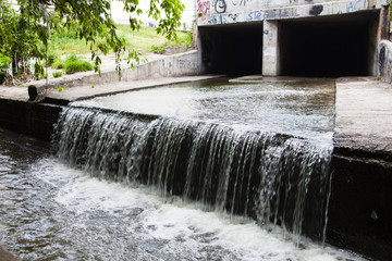 Water stream flowing out the underground tunnel - obrazy, fototapety, plakaty