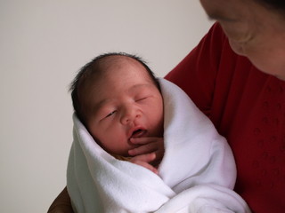 Newborn baby in the hand of his grandmother.