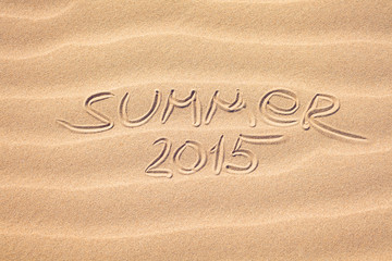 Fototapeta na wymiar Summer 2015 handwriting on the sea-sand with a wavy pattern