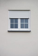 Modernes Fenster mit halboffenem Rollladen in grauer Fassade