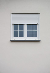 Modernes Fenster mit halboffenem Rollladen in grauer Fassade