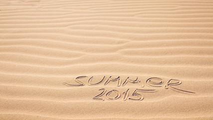 Fototapeta na wymiar Summer 2015 handwriting on the sea-sand with a wavy pattern