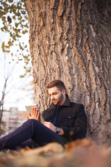 A smart young businessman using a tablet computer under a tree