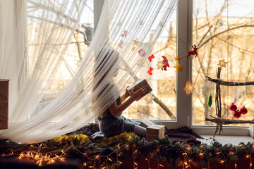 beautiful little girl with gifts on a windowsill