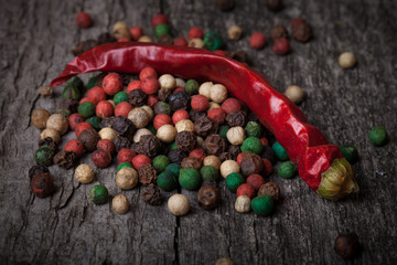 red hot chili peppers and peppercorns on an old wooden table