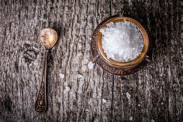 Fototapeta na wymiar sea salt in an old utensils and a small spoon on a wooden table