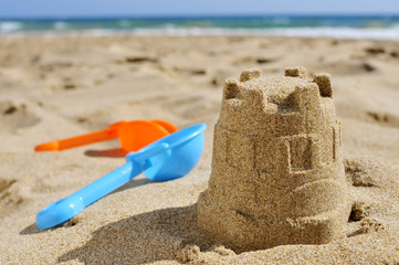 Fototapeta na wymiar sandcastle and toy shovels on the sand of a beach
