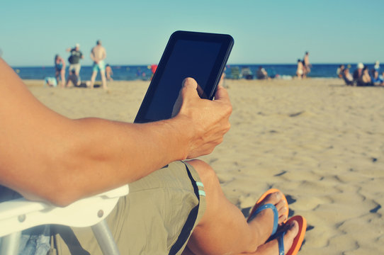 Young Man Using A Tablet On The Beach