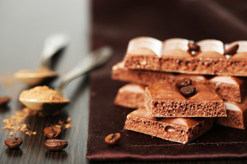 Tasty porous chocolate with coffee beans on table, close up