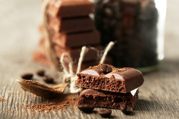 Tasty porous chocolate with coffee beans, on wooden table