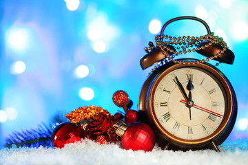 Alarm clock with Christmas decorations on bright background