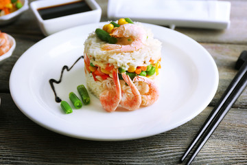 Boiled rice with shrimps and vegetables on wooden background