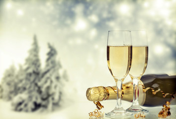 Glasses with champagne and bottle over winter background