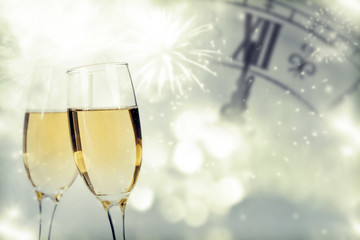 Glasses with champagne and clock close to midnight