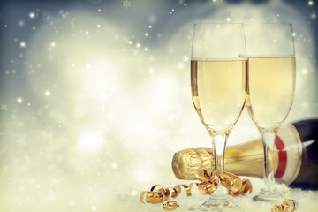 Glasses with champagne and bottle over holiday background