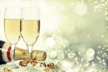 Glasses with champagne and bottle over holiday background