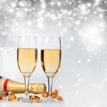 Glasses with champagne and bottle over holiday background