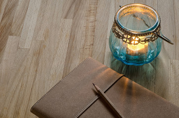 close-up of notebook with an old glass candle lantern