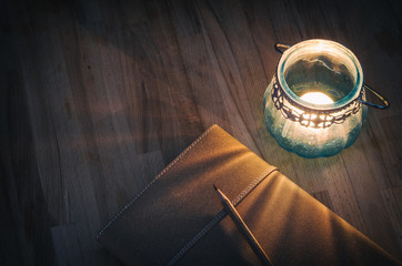 vintage notebook with an old candle on wooden table