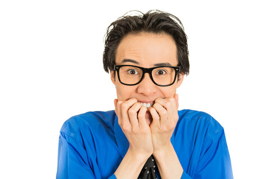 nerdy young guy with glasses biting his nails looking anxious