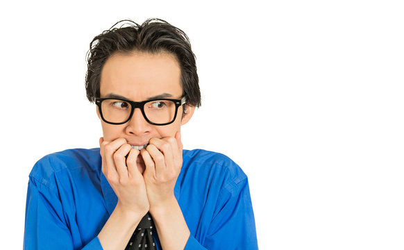 nerdy young guy with glasses biting his nails looking anxious