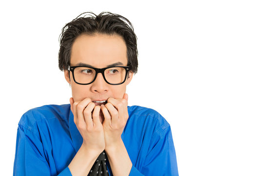 nerdy young guy with glasses biting his nails looking anxious