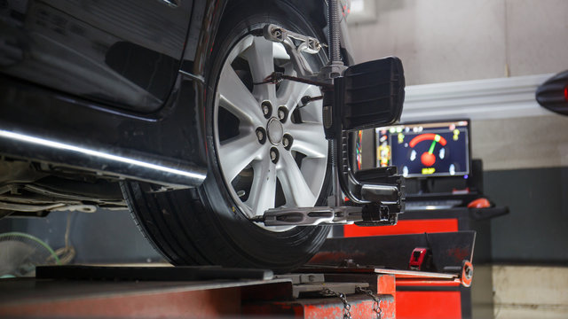 Car on stand with sensors on wheels for wheels alignment camber