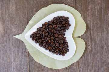 coffee grains and leaves over wooden background