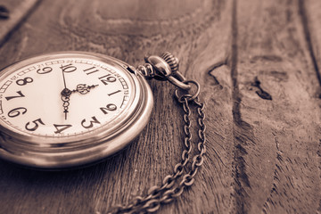 Pocket watch on wooden surface, vintage style light