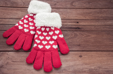 Obraz na płótnie Canvas Red knitted winter gloves on wooden surface
