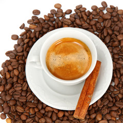 The white cup of espresso with grains and cinnamon stick