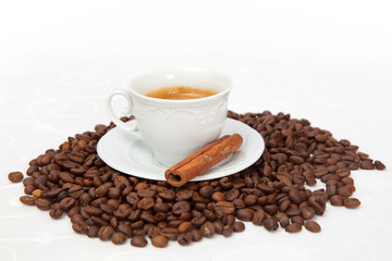 The cup of black coffee with grains and cinnamon stick