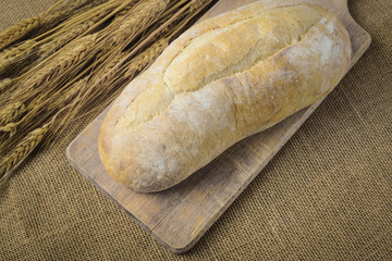 Bread on Bread Board with Wheat on Burlap Background