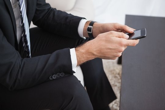 Businessman sending a text on his couch