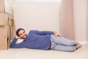 Happy man lying on floor with moving boxes