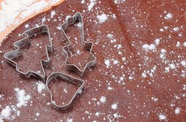 Cookie cutters lying on dough for gingerbread