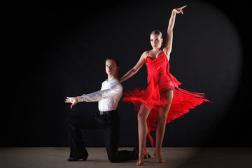 Latino dancers in ballroom against black background