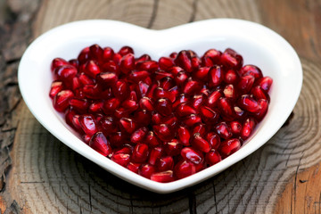 Pomegranate seeds on a plate in the form of heart