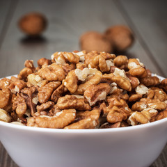 walnuts in the white bowl on wooden table