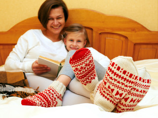 Mom and daughter lying on the bed in knitted socks