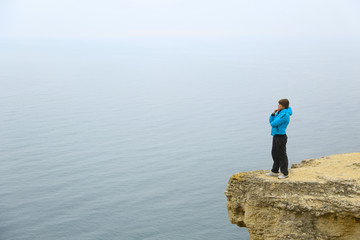 Fototapeta na wymiar beautiful woman on a cliff above the sea