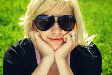 young girl in sunglasses sitting on grass